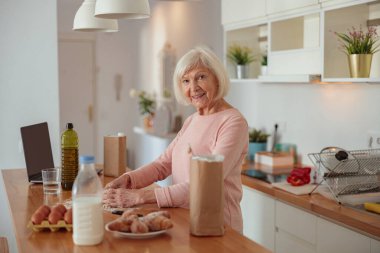 Evde mutfakta yemek pişiren son sınıf kadını.