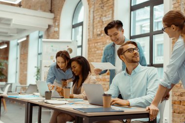 Ofiste beyin fırtınasında dizüstü bilgisayar kullanan yaratıcı iş ekibi