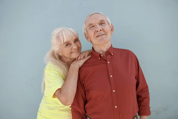 Счастливая пожилая женщина и мужчина стоят вместе, позируя перед камерой на светло-сером фоне — стоковое фото