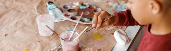 Шкільний хлопчик малює на папері з барвистими фарбами — стокове фото