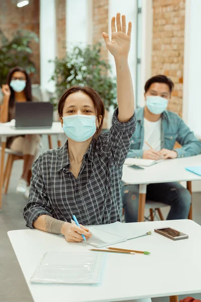 Estudiante en máscara facial levantando la mano para responder — Foto de Stock