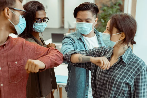 Estudiantes de pie y saludando golpeando codos en el lugar de trabajo — Foto de Stock