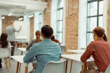 Öğrencilere ders sırasında resim çizelgesinin yanında duran öğretmen