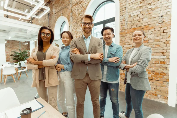 Gelukkige zakenmensen met wapens gekruist in het kantoor — Stockfoto