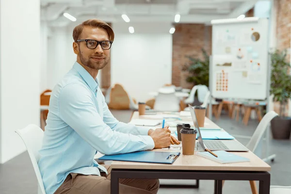 Guy à lunettes assis à une table dans un espace de coworking — Photo