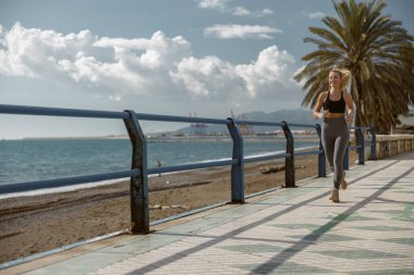 Halk parkında kaldırımda koşan genç bir kadın.