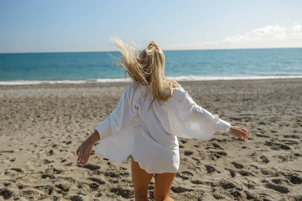 Rear view of young blonde lady running on the sunny beach — Foto de Stock