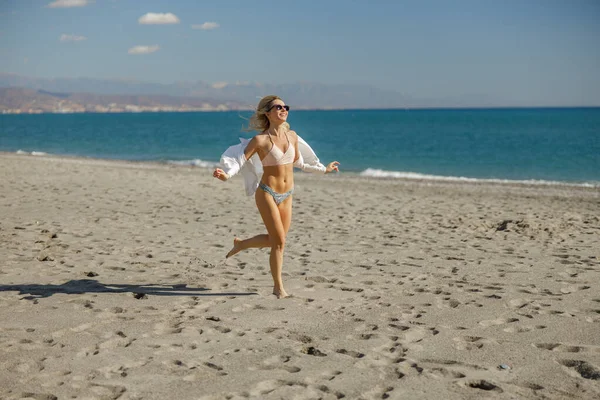 Izgalmas karcsú hölgy fut végig a parton egy napsütéses nyári napon — Stock Fotó