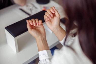 Kadın hasta kuaförde manikür prosedürü yaptırıyor.