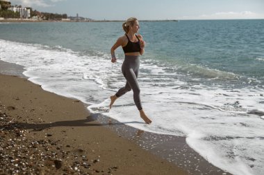Sportif genç dişi güzel sahil boyunca koşmaktan zevk alıyor.