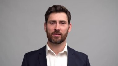 Takım elbiseli bir adam soru dinlerken düşünür sonra gülümser ve onaylayarak başını sallar.