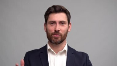 Takım elbiseli bir adam kamerayla konuşuyor, el kol hareketleri yapıyor, koç çevrimiçi ders veriyor.