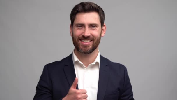 Handsome man in a suit looks at the camera, smiles and nods approvingly with a thumbs up — Stock videók