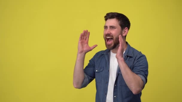 Un hombre positivo con barba pone las manos a un lado de la boca y grita, grita fuerte — Vídeos de Stock