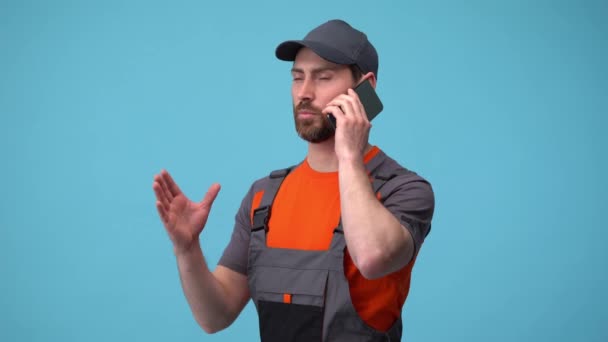 Delivery employee man in uniform talk on mobile phone isolated on blue background Clip Video