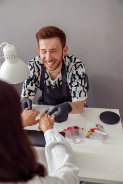 Manikür ustası güzellik merkezinde müşteri çivileri üzerinde çalışıyor.