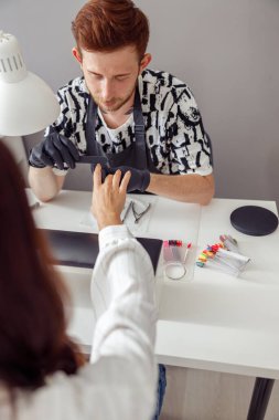 Manikür ustası güzellik merkezinde müşteri çivileri üzerinde çalışıyor.