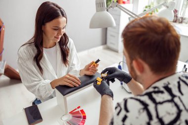 Neşeli kadın güzellik salonunda manikür yaptırıyor.