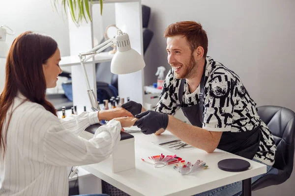 Neşeli kadın güzellik salonunda manikür yaptırıyor.