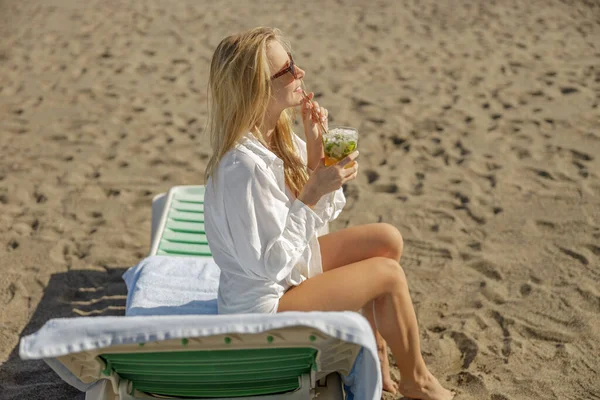 Blonde lady enjoying mohito cocktail and looking away on empty beach — Foto de Stock