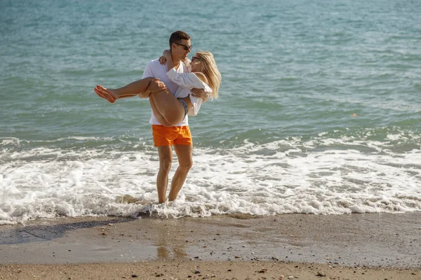 Kadını taşıyan bir adam, boş bir sahilde rüya gibi bir tatil sırasında birlikte eğleniyor.