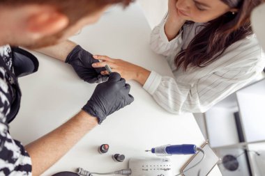 Stüdyoda manikür uzmanı müşteri için tırnak bakımı yapıyor.