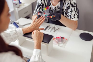 Kadın hasta kuaförde manikür prosedürü yaptırıyor.