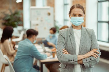 Young woman in mask standing in office