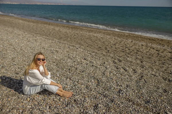 Güneşli bir yaz gününde kumsalda dinlenen gülümseyen bayan.