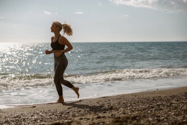 Sportif genç dişi güzel sahil boyunca koşmaktan zevk alıyor.