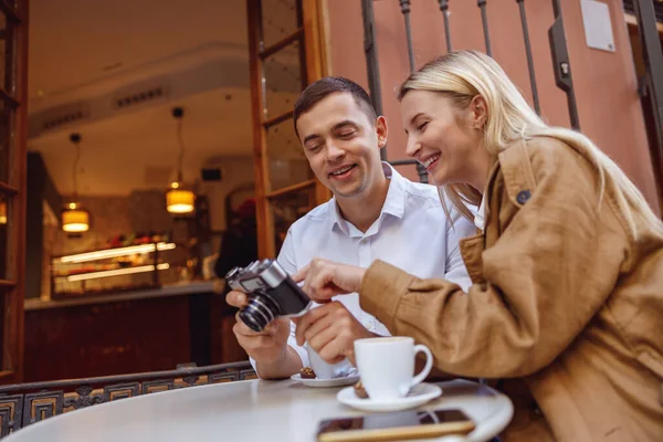 Smiling man and woman enjoying coffee and watching photos on retro camera — Stok fotoğraf