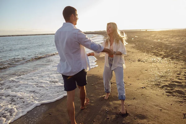 Full length of couple having fun while walking along the sandy beach barefoot — Stok Foto