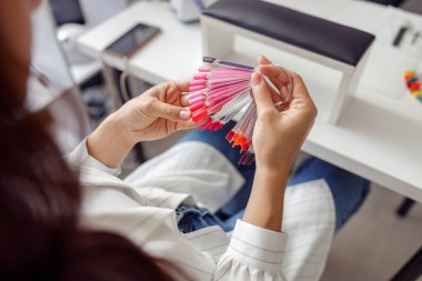 Güzellik salonunda tırnak cilası paleti olan kadın müşteri