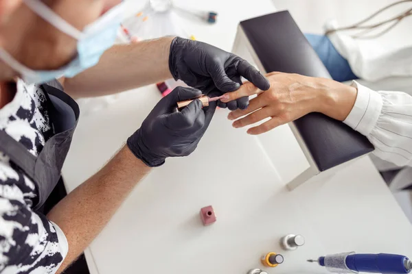 Creative nail master processing nails of his client in salon — 스톡 사진