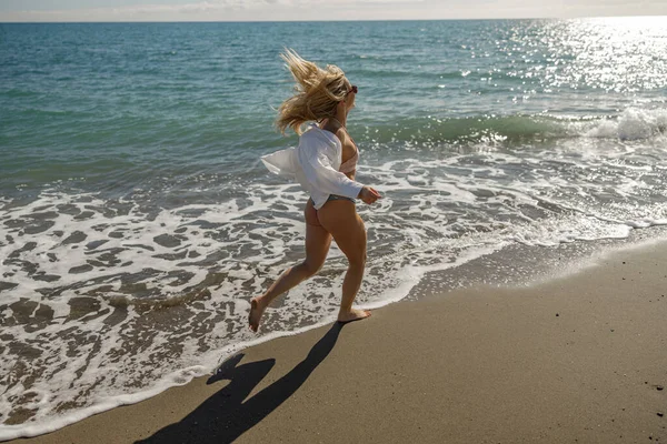 Lively woman running along the sea coast during summer vacation — Foto de Stock