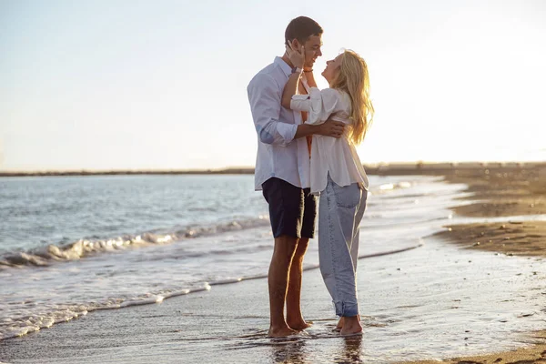 Full-length photo of young couple by the sea hugging and looking at each other — Stok Foto