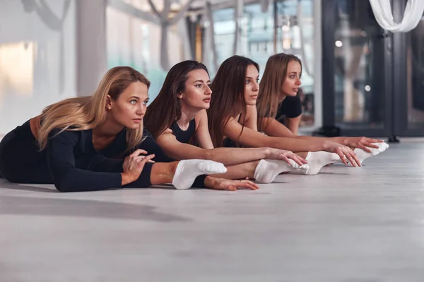Nahaufnahme junger sportlicher Frauen, die sich dehnen, während sie vor dem Luft-Yoga-Training auf einem Bindfaden sitzen — Stockfoto