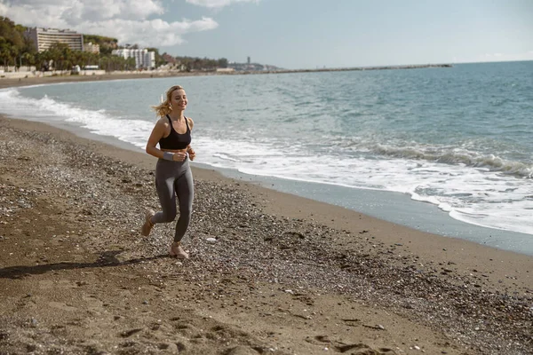 Sportieve jonge vrouw genieten van joggen langs prachtige kust — Stockfoto