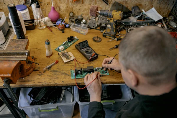 Close-up do reparador é placa de circuito de solda de dispositivo eletrônico na mesa — Fotografia de Stock