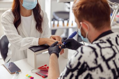 Güzellik salonundaki oje işlemleri için elektrikli makine kullanan manikür uzmanının arka planı