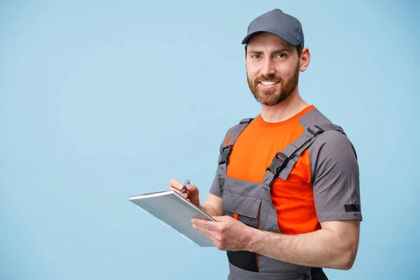 Smiling Delivery Man Berseragam Memegang Tablet Dan Membuat Catatan Kerja — Stok Foto