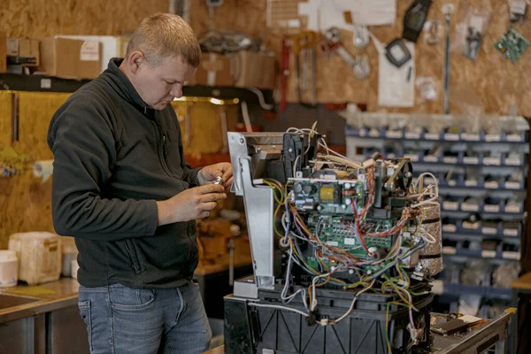 Male electrician repairing coffee machine in workshop. High quality photo