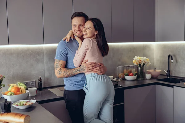 一对浪漫快乐的白人年轻夫妇在厨房拥抱中被刺伤的画像 — 图库照片