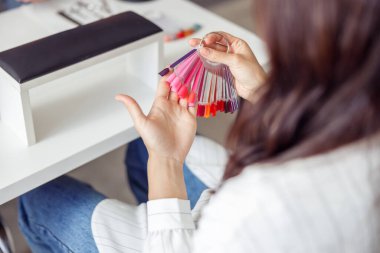 Manikür salonunda kadın müşterinin tırnak cilası rengini seçtiği arka manzara