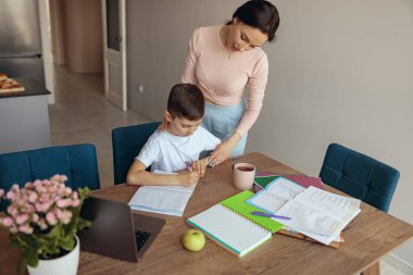 Çocuk rahat bir odada otururken annenin oğlunun ödevlerini kontrol edişine yukarıdan bak. Üst görünüm.