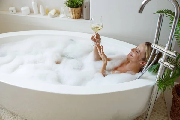 금발의 와인을 마시며 뜨거운 목욕을 — 스톡 사진