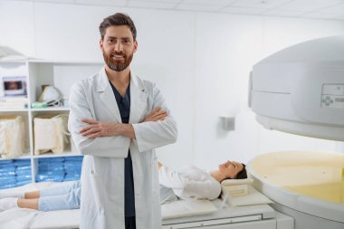 MRI veya CT taramasının arka planında hastayla birlikte radyoloji uzmanı. Yüksek teknolojili tıbbi ekipman