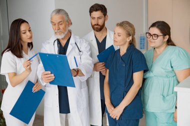 Hastanedeki stajyerlere hasta teşhisini tartışan profesyonel bir doktor.