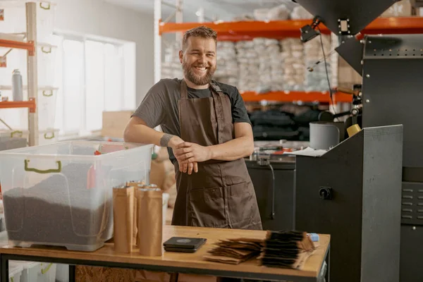 Smiling coffee roasting factory owner on his workplace looking camera. Blurred background