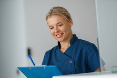 Doktor, klinikteki resepsiyonun yanındaki panoya not alıyor. Yüksek kalite fotoğraf